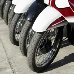 Rzędy motocykli gotowe do dpd transportu. Widoczne koła, opony i błotniki w kolorach białym, czarnym i czerwonym.