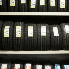 Rzędy opon samochodowych na półkach magazynu, gotowe do wysyłki DHL.