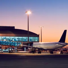 Samolot przy rękawie lotniskowym o zachodzie słońca. IATA co to? To kod lotniska, który pozwala zidentyfikować to miejsce.