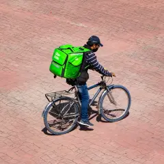 Kurier Uber Eats na rowerze z zieloną torbą. Zastanawiasz się, ile leci paczka z Chin do Polski?