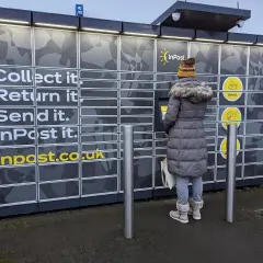 Kobieta korzysta z paczkomatu InPost, gdzie można odbierać, nadawać i zwracać paczki. To nowoczesne centrum logistyczne.