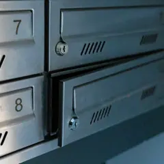 Metalowe skrytki pocztowe z numerami 7 i 8. Jedna z nich jest uchylona, ukazując zamek.