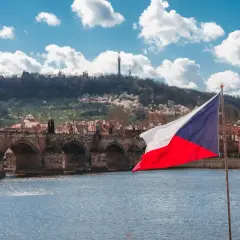 Flaga Czech na tle Mostu Karola w Pradze. Zastanawiasz się, ile idzie paczka z Czech do Polski?