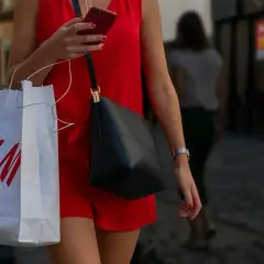Kobieta w czerwonej sukience trzyma torbę z logo H&M. Zastanawia się, ile dni na zwrot ma zakupiony towar.