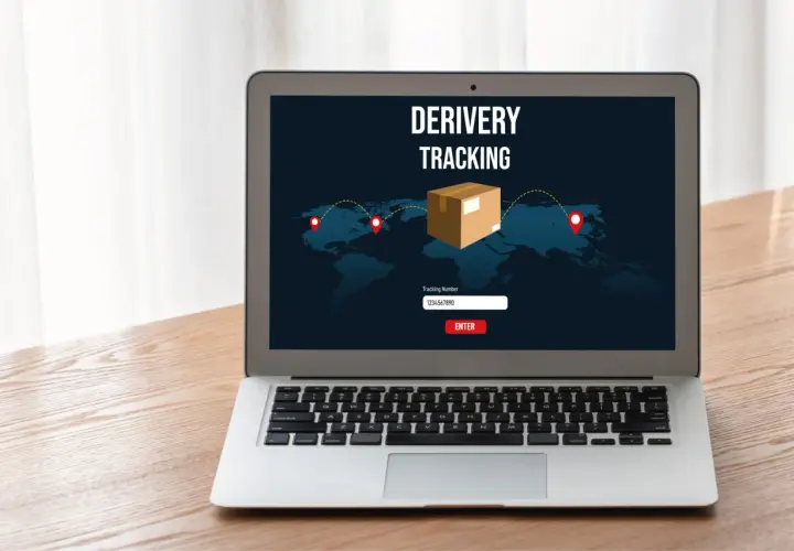 Laptop z ekranem pokazującym mapę świata i ikonę paczki. Widoczny jest napis "DERIVERY TRACKING" oraz pole do wpisania numeru przesyłki. To właśnie jest co to jest tracking.