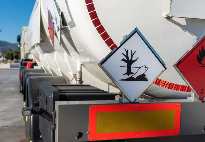 Zbliżenie na cysternę z oznaczeniami ADR. Widoczne symbole zagrożenia ekologicznego i łatwopalności.