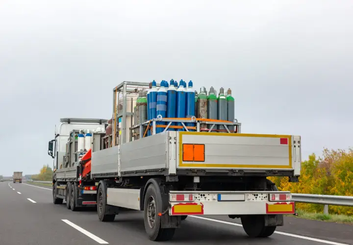 Ciężarówka z butlami gazowymi, klasa 2 ADR, jedzie autostradą.