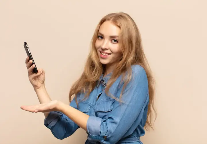 Uśmiechnięta blondynka trzyma telefon, prezentując etykietę cyfrową InPost.