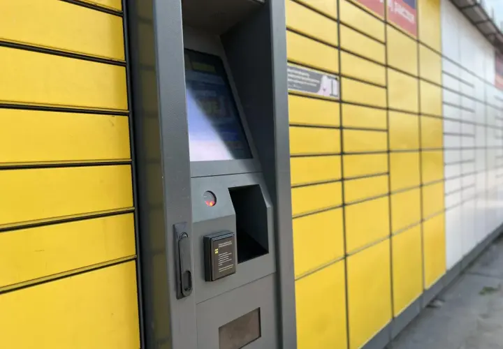 Automat paczkowy InPost, do którego rozwozi kurier. Żółte skrzynki i szary panel sterowania.