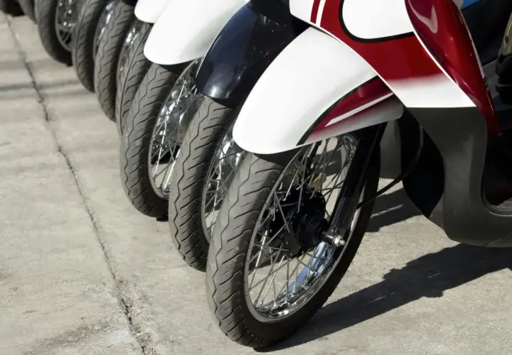 Rzędy motocykli gotowe do dpd transportu. Widoczne koła, opony i błotniki w kolorach białym, czarnym i czerwonym.