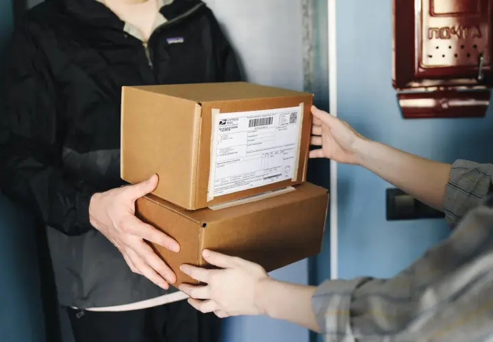 Dwie osoby przekazują sobie paczki. Na jednej z nich widoczna jest etykieta z kodem kreskowym. Ile cyfr ma kod nadania InPost?