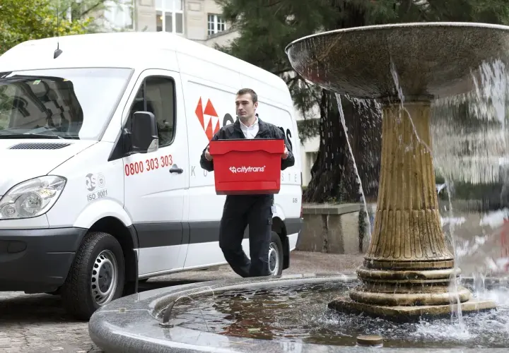 Kurier Citytrans z czerwoną skrzynką, gotowy do dostarczenia paczki tego samego dnia.