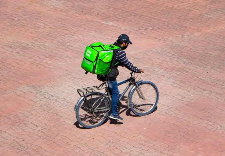 Kurier Uber Eats na rowerze z zieloną torbą. Zastanawiasz się, ile leci paczka z Chin do Polski?