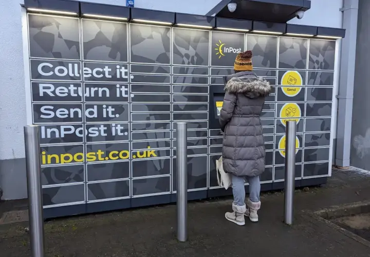 Kobieta korzysta z paczkomatu InPost, gdzie można odbierać, nadawać i zwracać paczki. To nowoczesne centrum logistyczne.