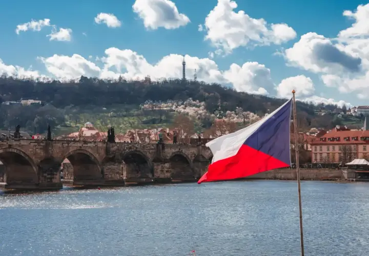 Flaga Czech na tle Mostu Karola w Pradze. Zastanawiasz się, ile idzie paczka z Czech do Polski?