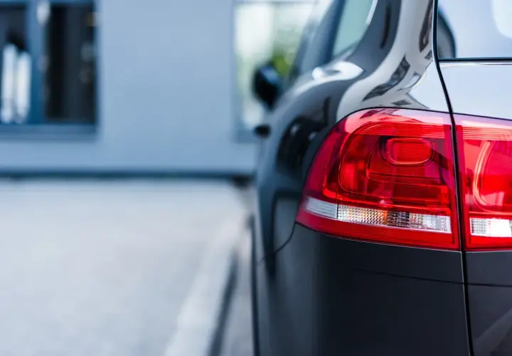 Ciemny samochód, gotowy na uber paczkę. Błyszczący lakier i czerwone światła z tyłu.