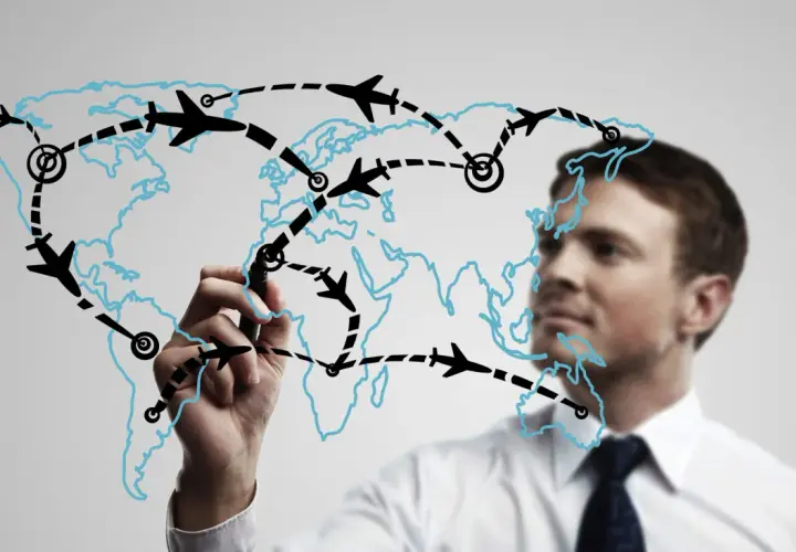 Mężczyzna rysuje na mapie świata trasy lotnicze, planując globalną logistykę.