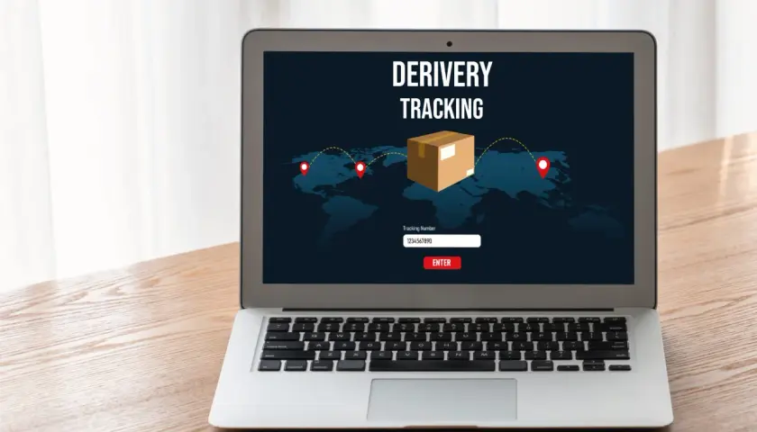 Laptop z ekranem pokazującym mapę świata i ikonę paczki. Widoczny jest napis "DERIVERY TRACKING" oraz pole do wpisania numeru przesyłki. To właśnie jest co to jest tracking.