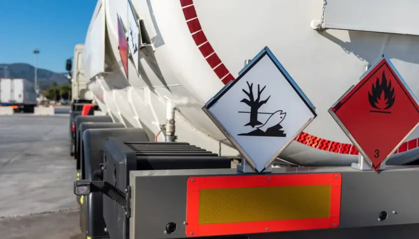 Zbliżenie na cysternę z oznaczeniami ADR. Widoczne symbole zagrożenia ekologicznego i łatwopalności.