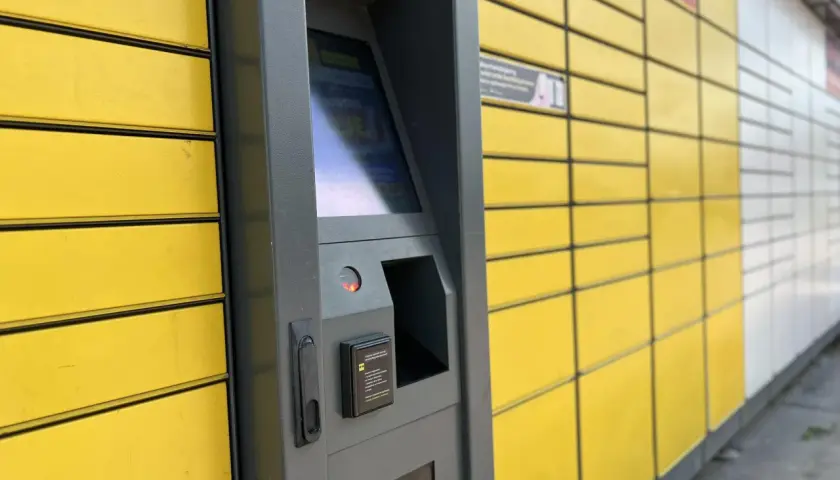 Automat paczkowy InPost, do którego rozwozi kurier. Żółte skrzynki i szary panel sterowania.