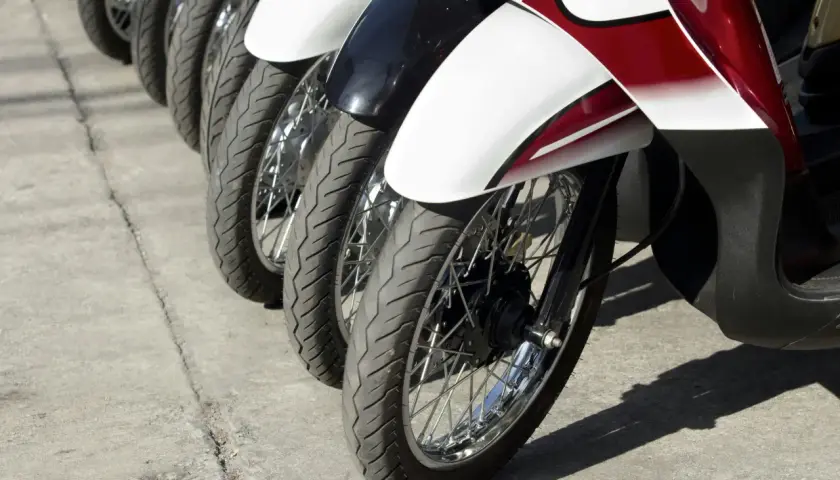 Rzędy motocykli gotowe do dpd transportu. Widoczne koła, opony i błotniki w kolorach białym, czarnym i czerwonym.