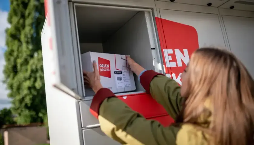 Kobieta wkłada paczkę gabarytową do paczkomatu ORLEN Poczta.