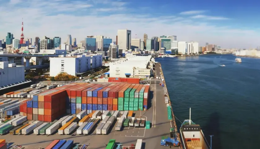 Kontenery czekają na załadunek. Ta wielka paczka do Japonii popłynie statkiem przez ocean, mijając nowoczesne miasto.