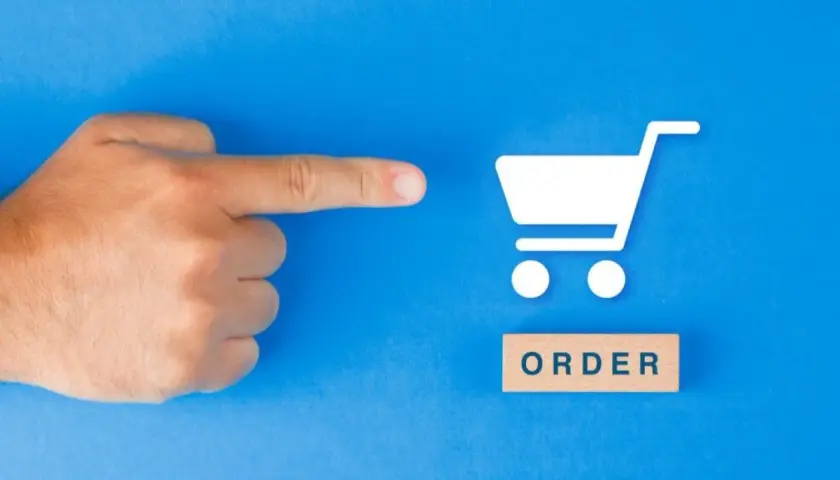 Palec wskazujący na ikonę koszyka zakupowego i drewniany klocek z napisem "ORDER". To symbol złożenia zamówienia.