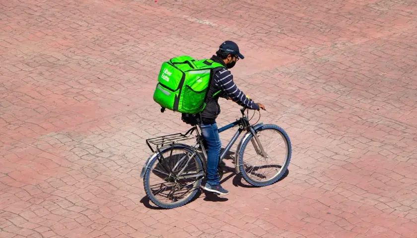 Kurier Uber Eats na rowerze z zieloną torbą. Zastanawiasz się, ile leci paczka z Chin do Polski?