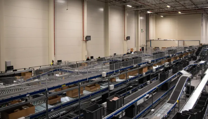 Nowoczesne centrum logistyczne z taśmociągami i pojemnikami, obsługujące usługi e-commerce.