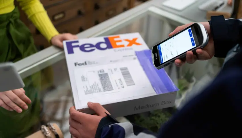 Osoba skanuje kod kreskowy na paczce FedEx za pomocą urządzenia mobilnego, realizując pointpack śledzenie.