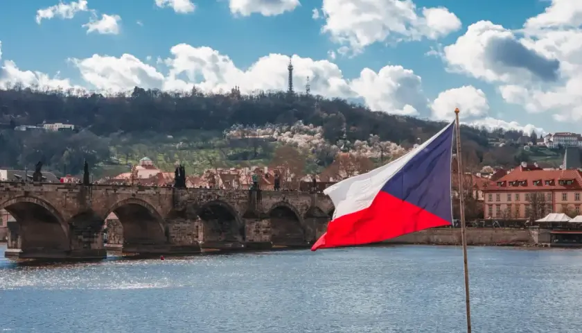 Flaga Czech na tle Mostu Karola w Pradze. Zastanawiasz się, ile idzie paczka z Czech do Polski?
