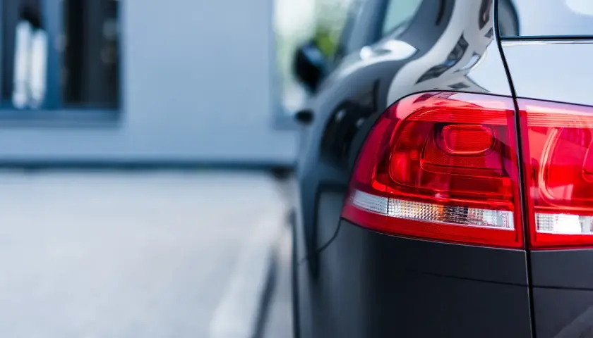 Ciemny samochód, gotowy na uber paczkę. Błyszczący lakier i czerwone światła z tyłu.