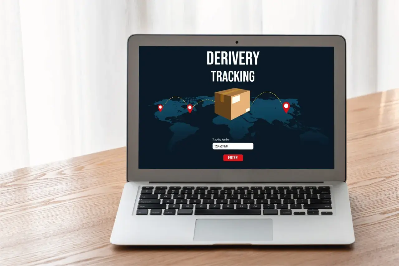 Laptop z ekranem pokazującym mapę świata i ikonę paczki. Widoczny jest napis "DERIVERY TRACKING" oraz pole do wpisania numeru przesyłki. To właśnie jest co to jest tracking.