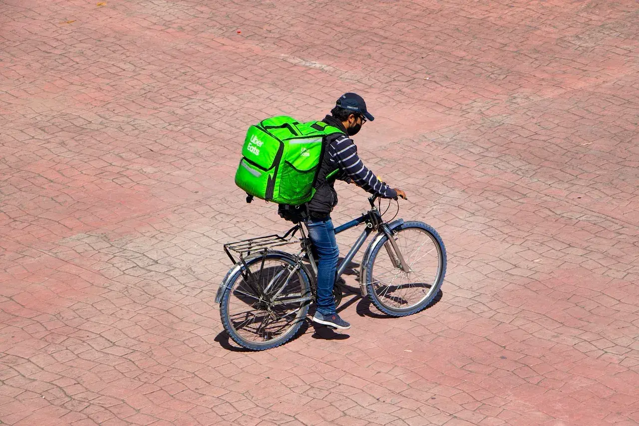 Kurier Uber Eats na rowerze z zieloną torbą. Zastanawiasz się, ile leci paczka z Chin do Polski?