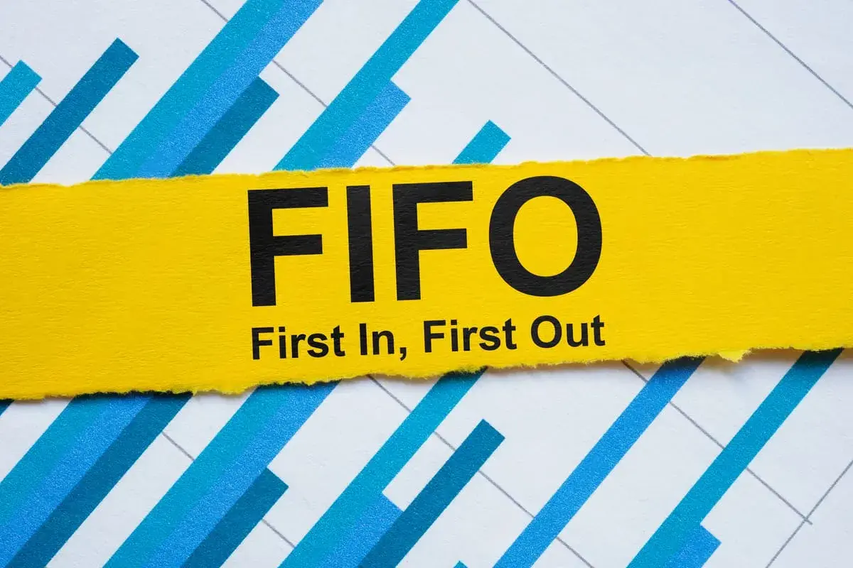 Żółty pasek z napisem FIFO (First In, First Out) na tle wykresu. Zasada FIFO w praktyce.