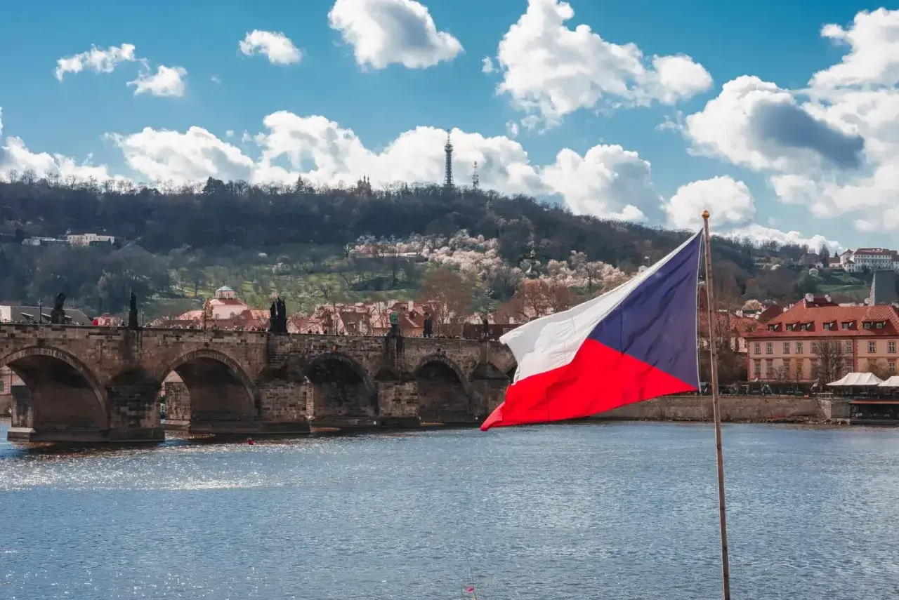 Flaga Czech na tle Mostu Karola w Pradze. Zastanawiasz się, ile idzie paczka z Czech do Polski?