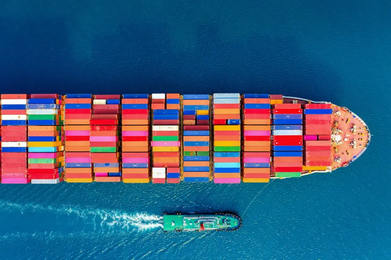Kontenerowiec z kolorowymi kontenerami na morzu. CIF Incoterms co oznacza? Ubezpieczenie i fracht do portu docelowego.