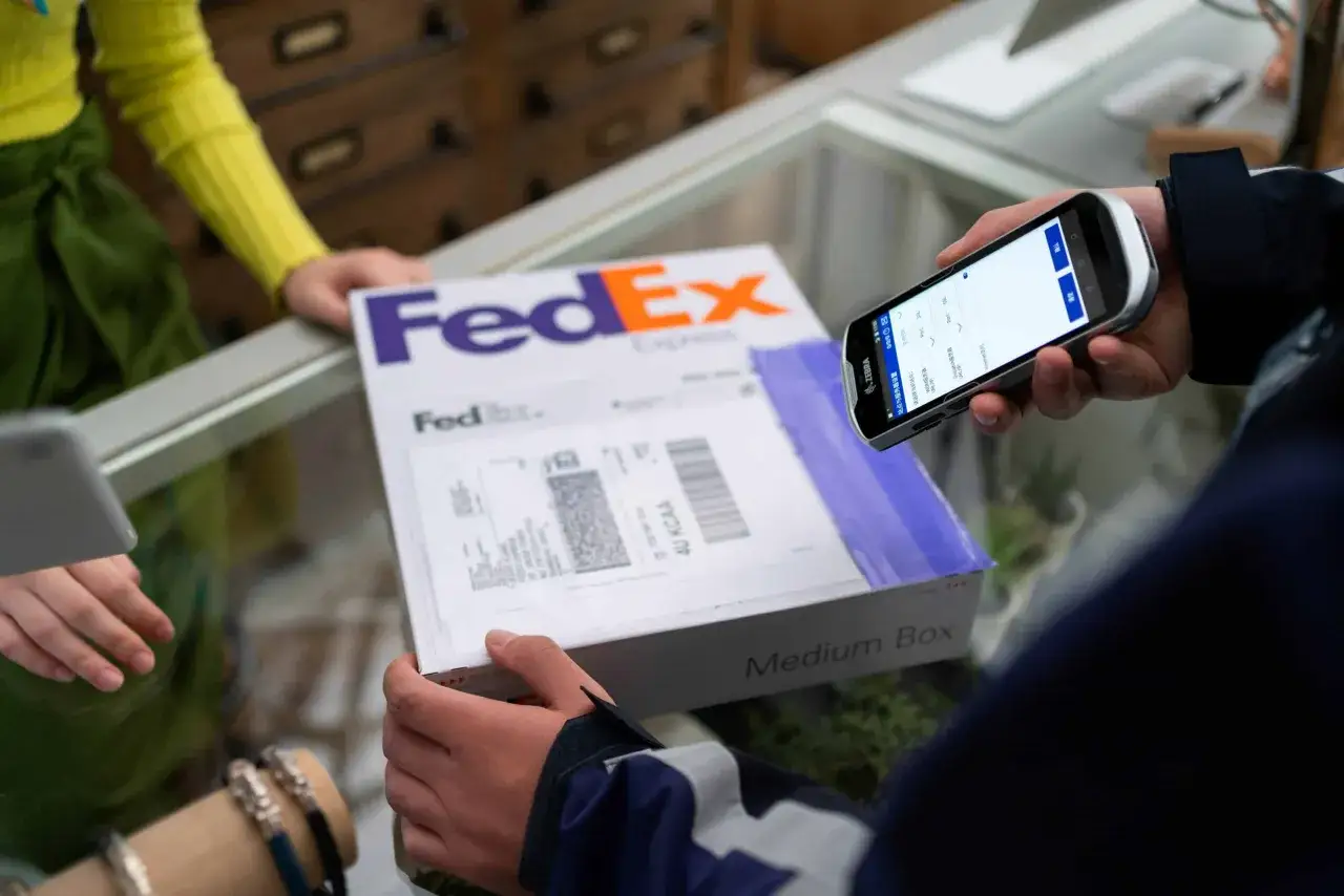 Osoba skanuje telefonem paczkę FedEx, realizując pointpack śledzenie.