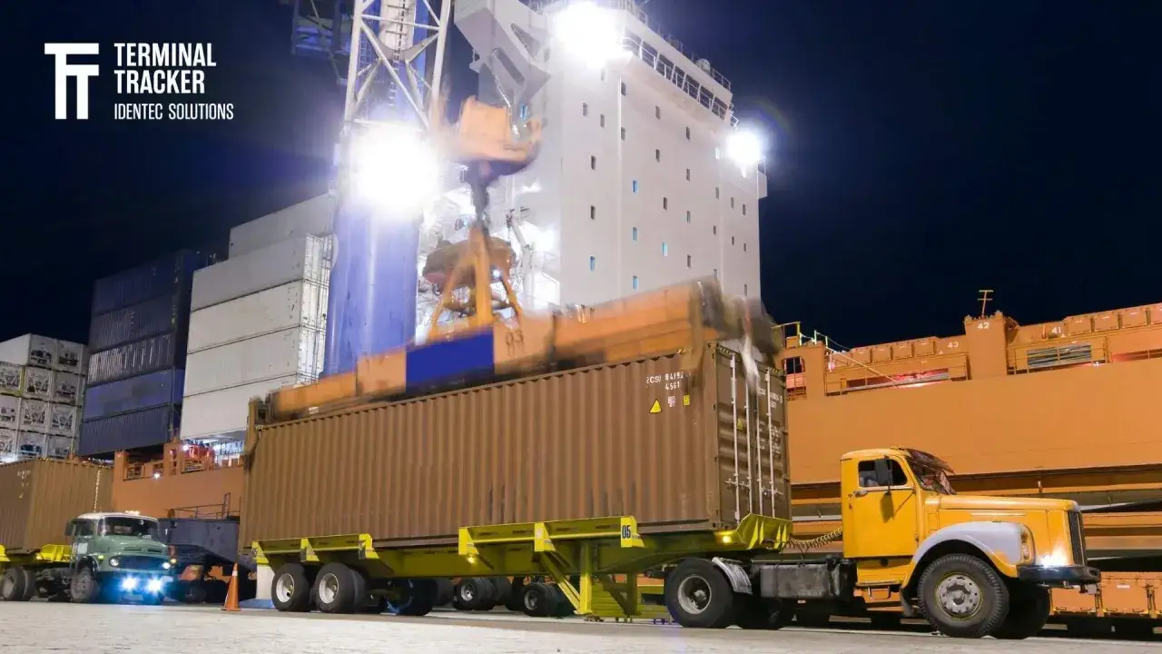 Przeładunek kontenerów w nocy. Ciężarówka czeka na rozładunek, by uniknąć opłat za demurrage.