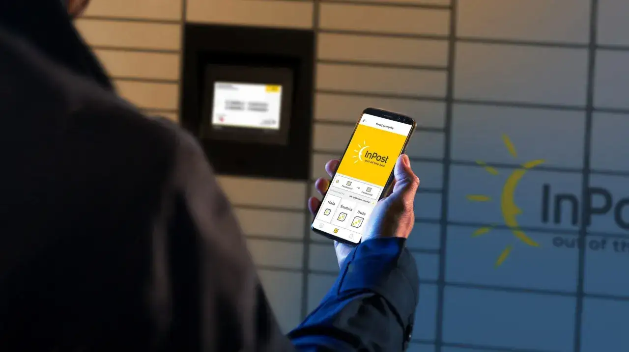 Mężczyzna trzyma smartfon z aplikacją InPost, planując sizer zwrot paczki przy automacie.